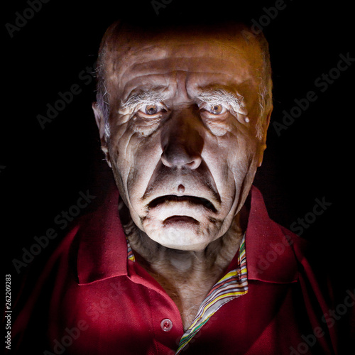 Portrait of old and sad caucasian man. Low-key lighting. Isolated on black.