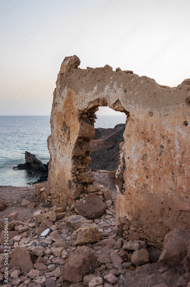 Wall with gate of a building demolished on a cliff facing the sea