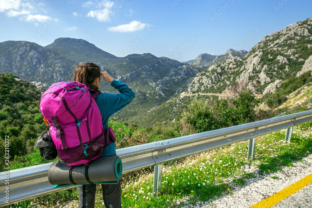 Woman hitchhike on the roadside with beauty mountains.