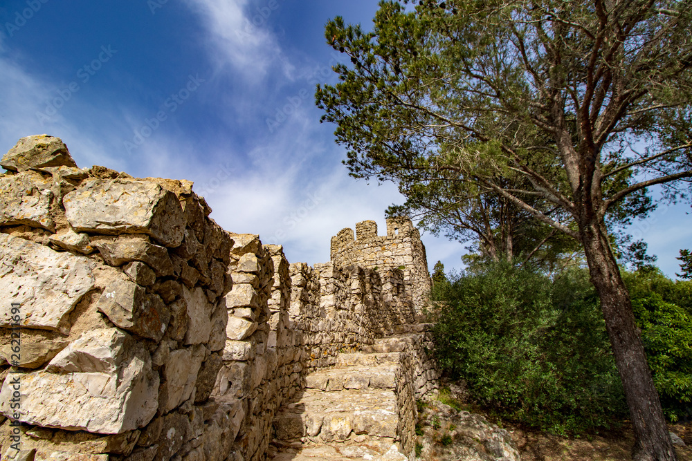 Blue sky and white clouds in the background and in the foreground part of the walls of a castle