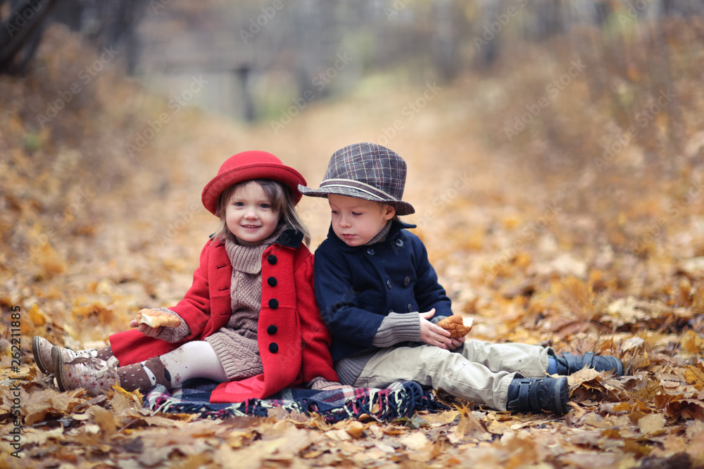 boy and girl are sitting on autumn leaves and eat boy and girl are sitting on autumn leaves and eat