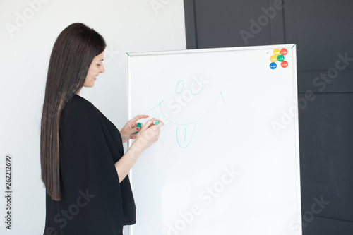 Young woman planning writing day plan on white board, holding marker in right hand.