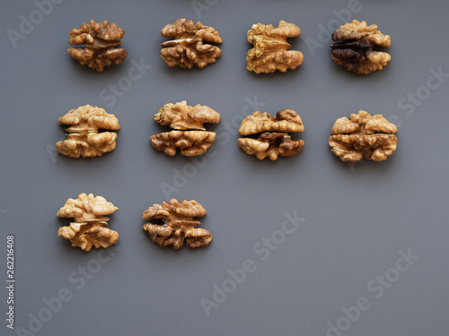 Row of walnuts on gray and blue textured background with a copyspace; Top view of kernel halves; close up food photo from above; snack and nutrition, vitamins and minerals;