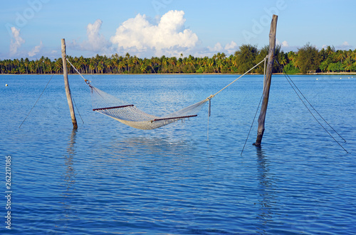 Hammock with a view, planted in the azure waters of the Bora Bora lagoon, French Polynesia