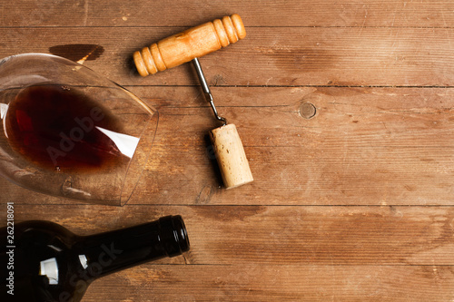 Botella de vino tinto con copa y sacacorchos sobre fondo de madera rústico. Vista superior. Copy space photo