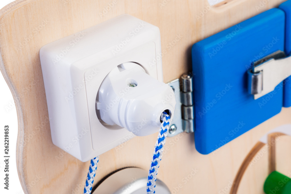 Close-up socket with a plug and wire on a wooden busy board- educational toy for children, babies on a white isolated background. A toy for entertaining children and relaxing parents Close-up socket with a plug and wire on a wooden busy board- educational toy for children, babies on a white isolated background. A toy for entertaining children and relaxing parents