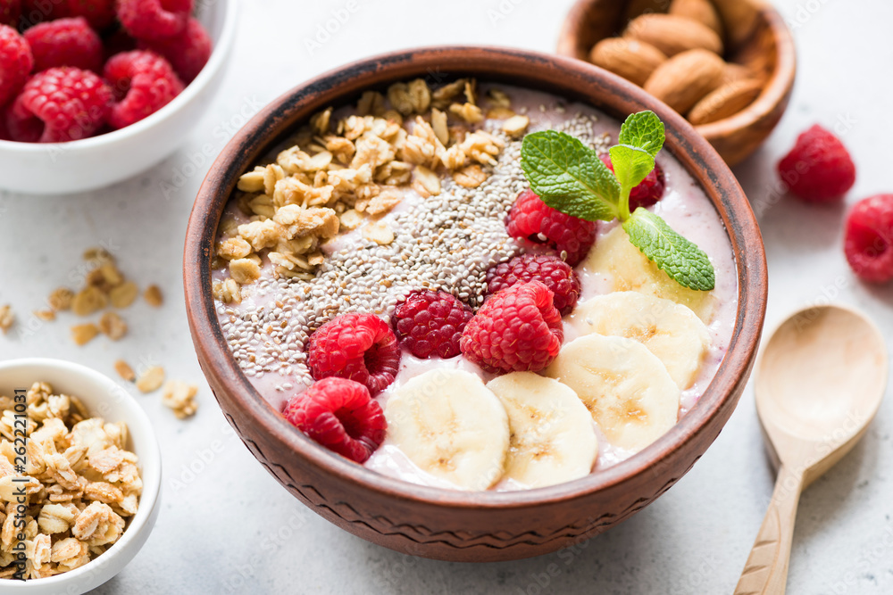 Superfood acai smoothie bowl with toppings such as banana slices, fresh raspberries, chia seeds and granola. Closeup view. Concept of clean eating, dieting, weight loss, vegan or vegetarian diet Superfood acai smoothie bowl with toppings such as banana slices, fresh raspberries, chia seeds and granola. Closeup view. Concept of clean eating, dieting, weight loss, vegan or vegetarian diet