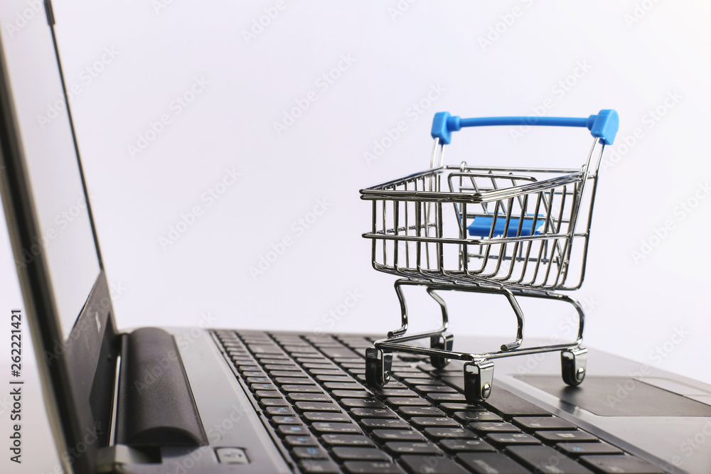 Shopping cart is on the laptop. Online sales concept.