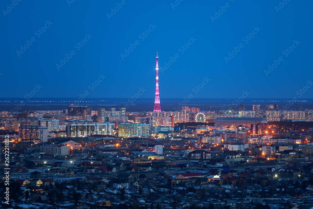 Aerial view of Yakutsk, Yakutia skyline with TV tower illuminated in bright colors and center of city in beautiful post sunset twilight during blue hour