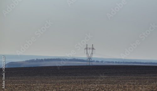 Power line in the field. Fog on the horizon.
