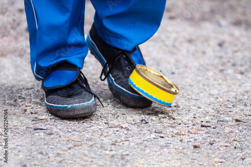 Old used can of street football game and legs in sneakers.