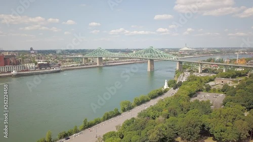 Cinematic drone / aerial footage moving forwards showing Jacques Cartier Bridge of Montreal seem from Jean Drapeau Park during summer season. photo