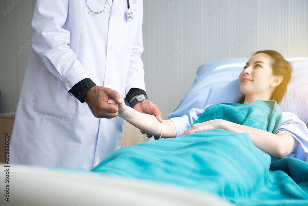 Fototapeta premium Doctor giving a consultation and encouragement to patient together,Senior doctor reassuring to asian female patient in hospital room