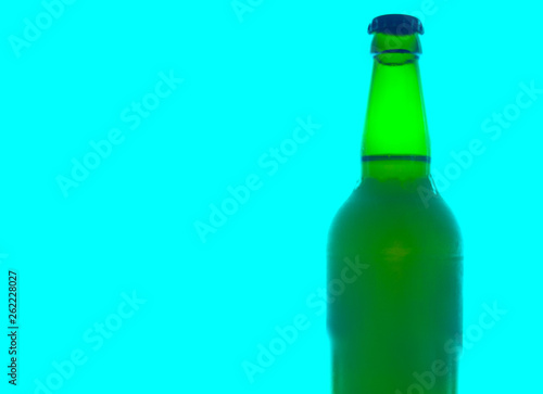 Green bottle with black cap isolated on light blue background with space