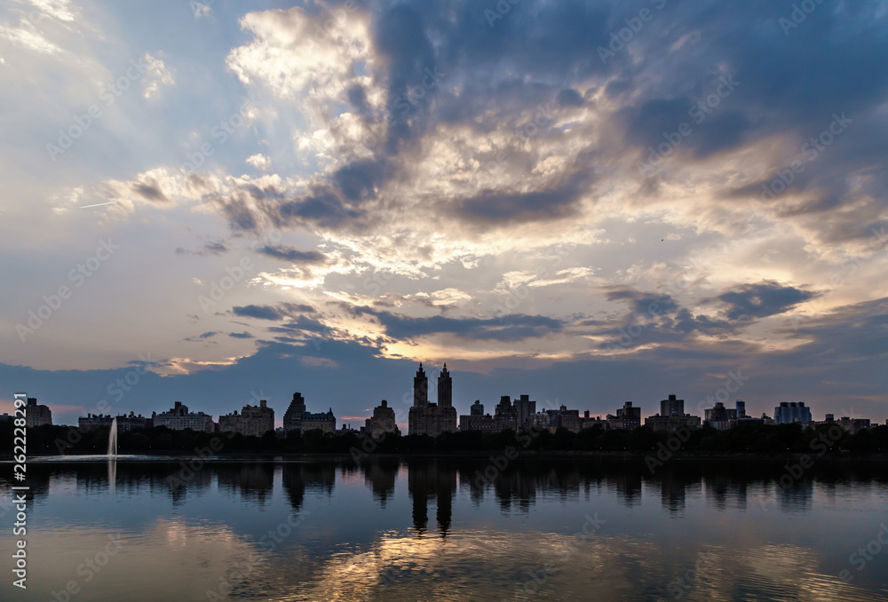 Skyline of buildings along Central Park West viewed from Jackie Kennedy Onassis Reservoir in New York City, ducks in the foreground, blue hours. Travel USA.