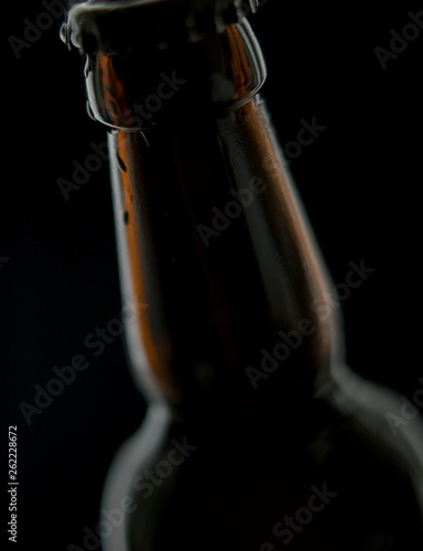 Black beer bottle with water drops isolated on black background with space
