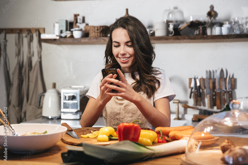Beautiful young woman wearing apron cooking vegetables Beautiful young woman wearing apron cooking vegetables
