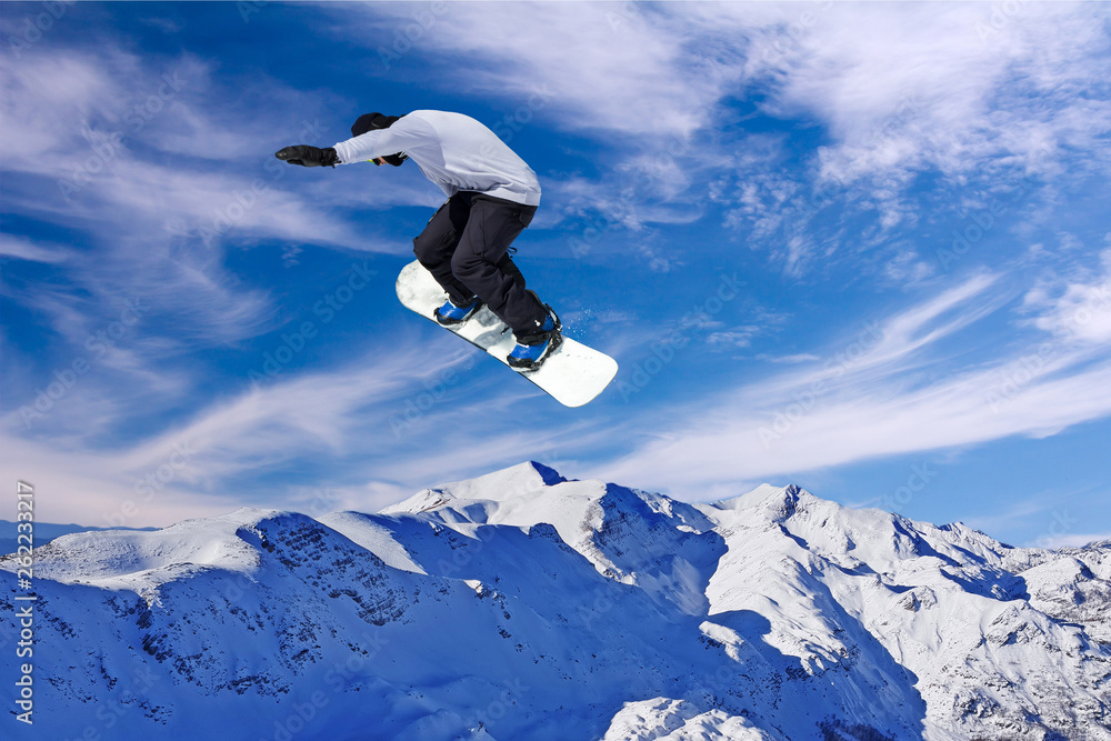 Snowboarder jumping through air with blue sky in background Snowboarder jumping through air with blue sky in background