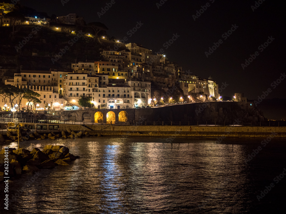 Nightly view of Amalfi city at night on coast line, Italy. April, 2019