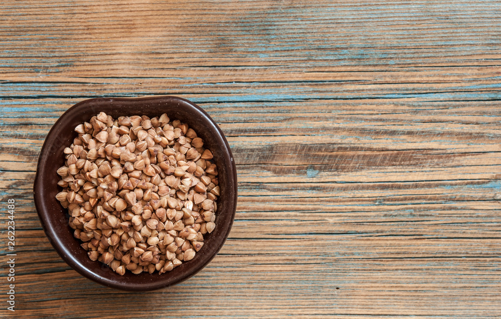 Raw buckwheat in a wooden bowl, top view Raw buckwheat in a wooden bowl, top view