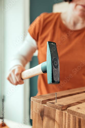 Fotografie, Obraz Female carpenter hammering nail into wooden crate