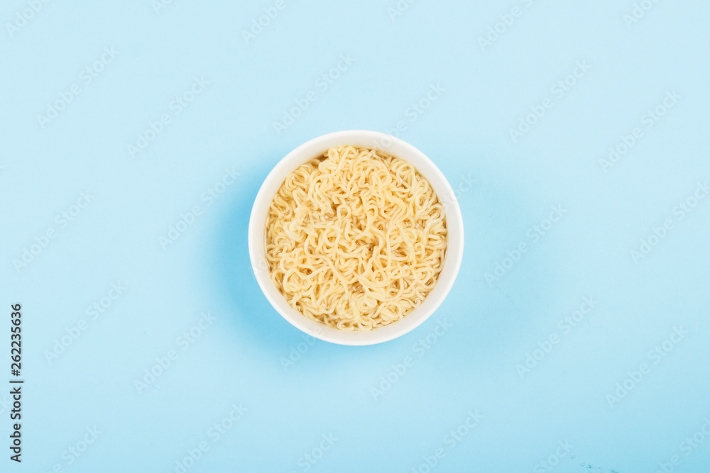 Asian instant noodles on a white plate against a blue background. The concept of convenience foods, fast food, junk food. Flat lay, top view. Asian instant noodles on a white plate against a blue background. The concept of convenience foods, fast food, junk food. Flat lay, top view.