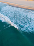 Aerial view of breaking waves on the beach coastline.