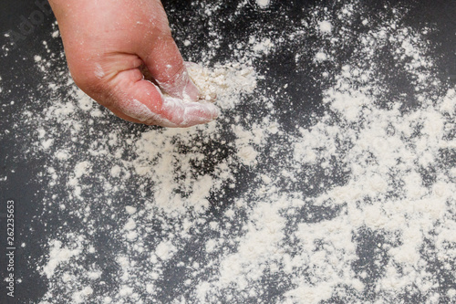 White flour is poured on a black table before cooking cookies