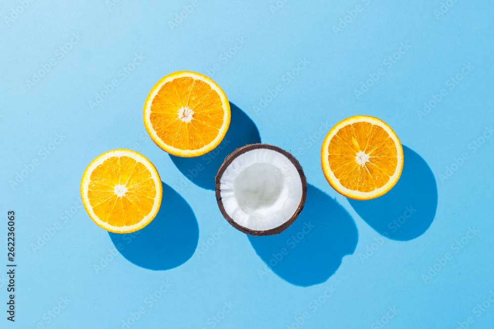 Cut oranges and coconuts on a blue background. Hard light. Tropics concept, healthy food, breakfast, diet, vacation. Flat lay, top view. Cut oranges and coconuts on a blue background. Hard light. Tropics concept, healthy food, breakfast, diet, vacation. Flat lay, top view.