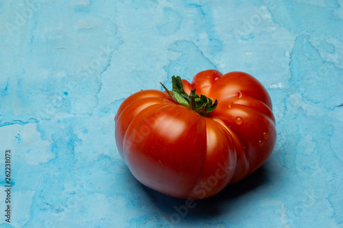 Beautiful Brandywine red tomatoes on grunge blue background photo