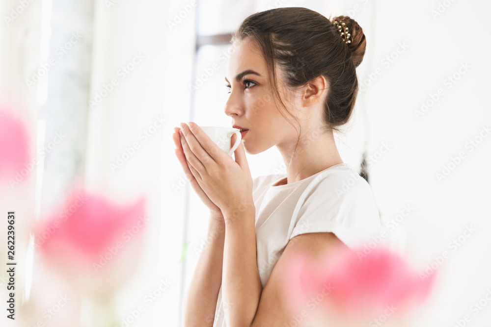 Beautiful young student girl drinking coffee posing indoors. Beautiful young student girl drinking coffee posing indoors.