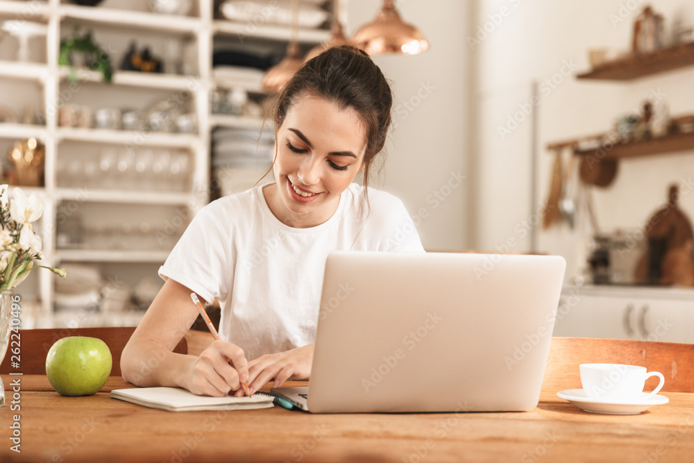Beautiful young student girl with apple indoors using laptop computer. Beautiful young student girl with apple indoors using laptop computer.