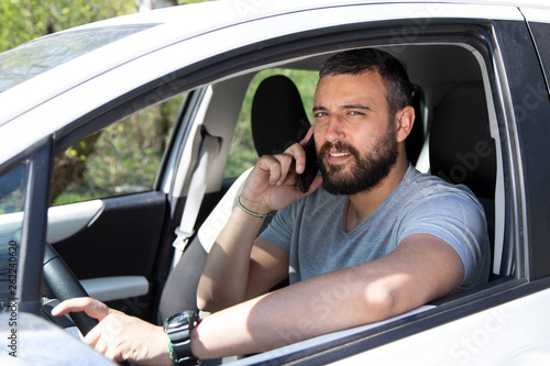 Man talking at mobile phone while driving a car.