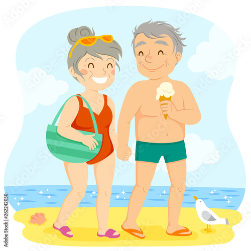 Older couple in swimsuits walking happily on the beach