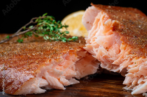 A half-torn piece of smoked salmon fillet on a wooden Board on a dark background