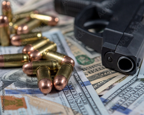 Firearm with ammunition on a background of United States currency. Selective focus