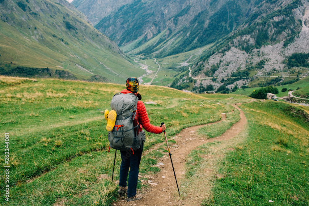 Naklejka premium woman with a backpack, looking on valley. Hiking around Mont Blanc, France, European Alps
