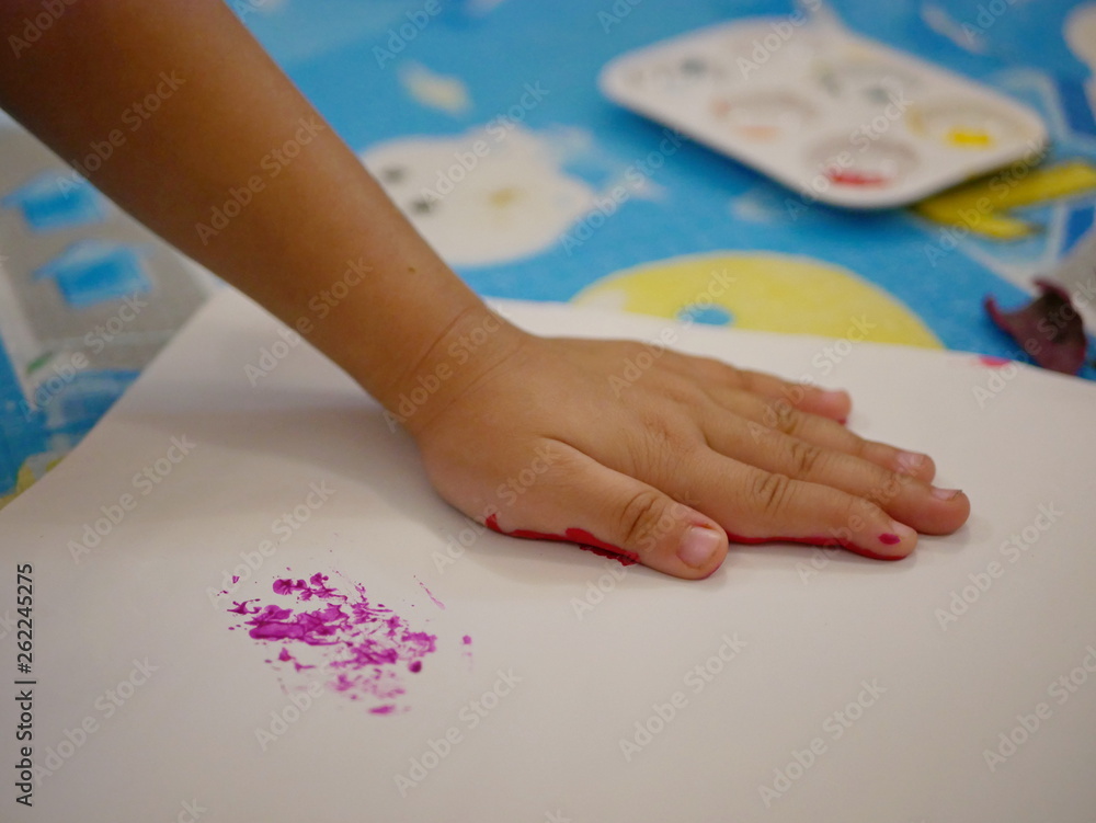 Close up of a hand of a little baby with red color pressing down on white paper - baby handprint / fingerprint painting Close up of a hand of a little baby with red color pressing down on white paper - baby handprint / fingerprint painting