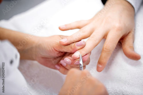 Manicurist using cuticle scissors for nail treatment