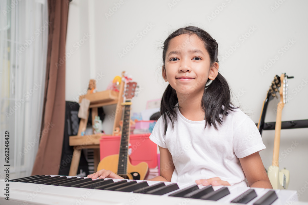 Asian little girl learning to play piano keyboard synthesizer with happiness Asian little girl learning to play piano keyboard synthesizer with happiness
