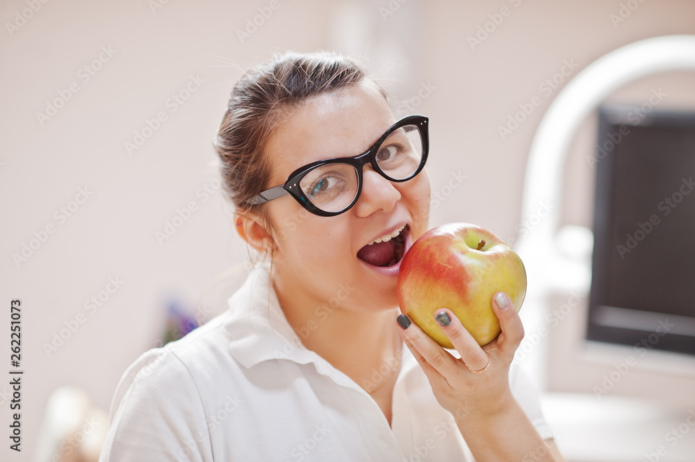 Portrait of female dentist woman standing in her dentistry office and eating an apple. Portrait of female dentist woman standing in her dentistry office and eating an apple.