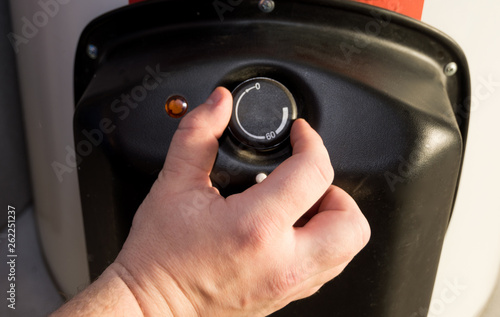 Closeup of man hands setting the temperature of water in Electric Boiler