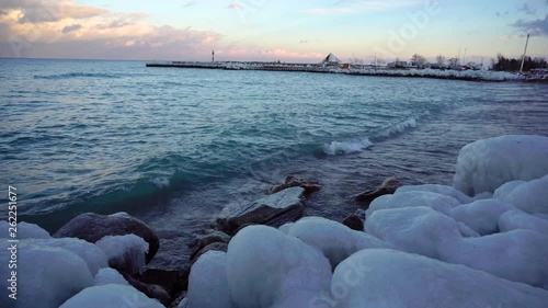 Waves crashing onto an ice covered beach at sunset in The Blue Mountains, Canada. photo