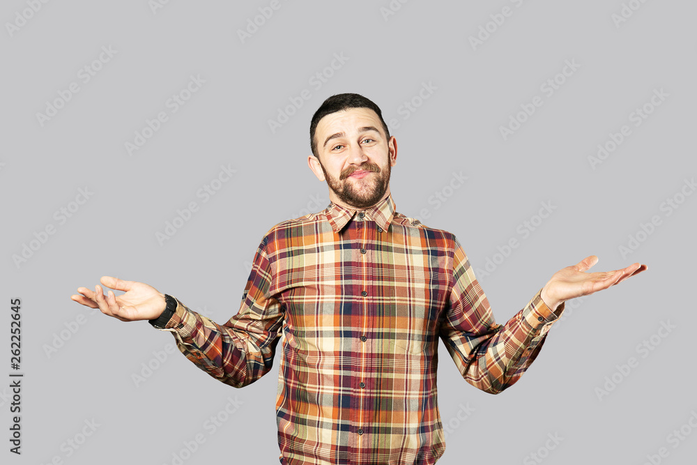 Young handsome man with facial hair posing over gray wall with a lot of copy space for text. Portrait of confident bearded male, wearing hipster slim fit checkered shirt. Isolated, background. Young handsome man with facial hair posing over gray wall with a lot of copy space for text. Portrait of confident bearded male, wearing hipster slim fit checkered shirt. Isolated, background.