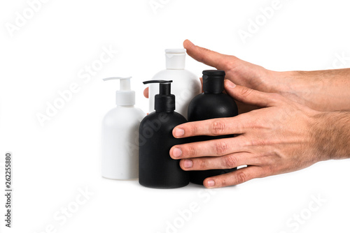 Partial view of man holding cosmetic bottles on white