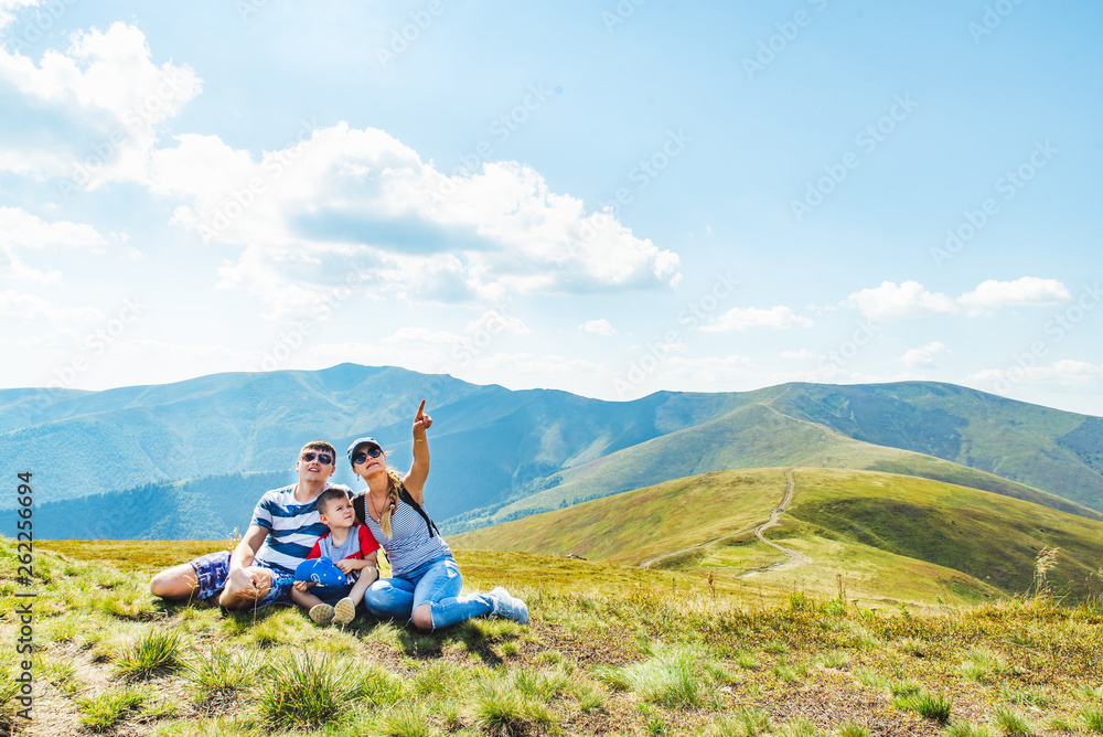 young family on the top of the peak. woman pointing somewhere. travel concept