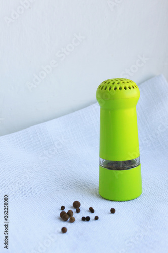 Black peppercorns in ancient metal mortar with pestle on linen background photo