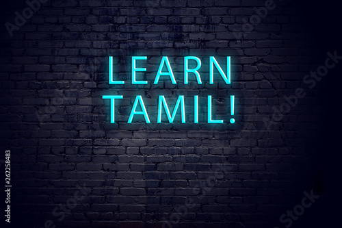 Brick wall and neon sign with inscription. Concept of learning tamil photo