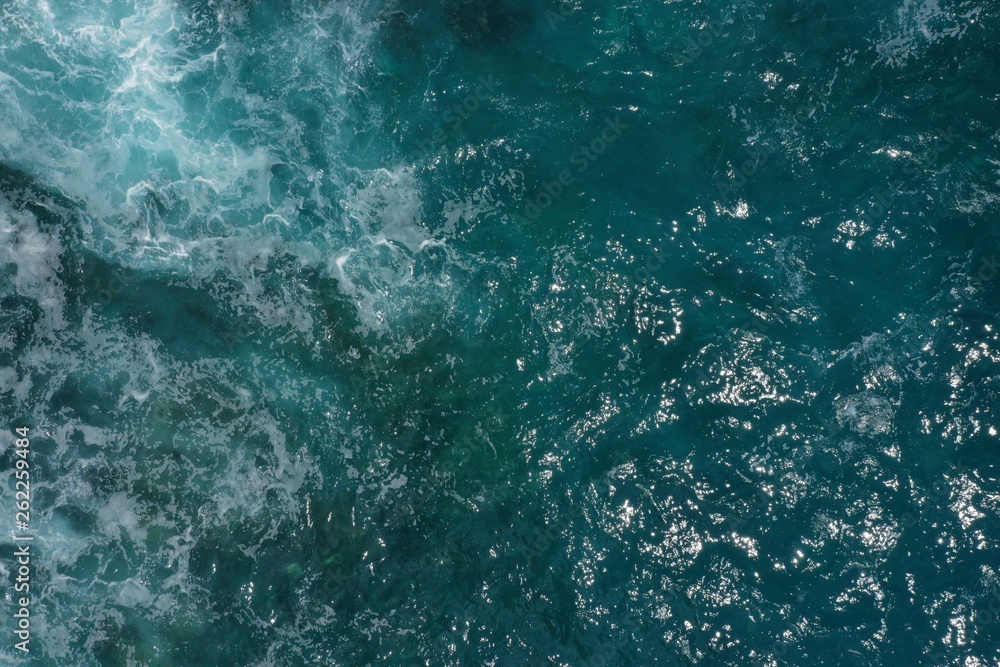 Fototapeta premium Aerial view of Indian ocean and foaming waves breaking on rocks in Bali, Indonesia.
