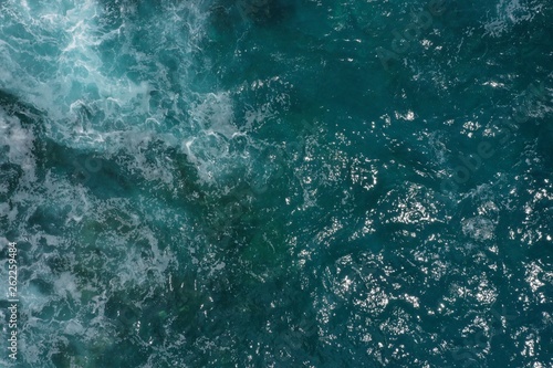 Aerial view of Indian ocean and foaming waves breaking on rocks in Bali, Indonesia.